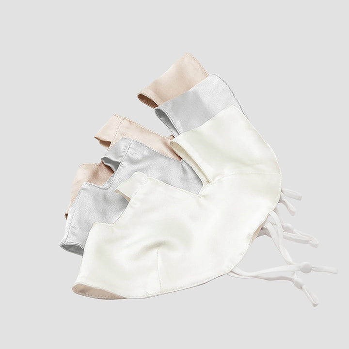Three Beauty Silk Face Masks by SusanSilk in beige, silver, and white are laid out side by side on a light gray background. Each mask features white adjustable ear loops, embodying the luxurious craftsmanship that defines SusanSilk products.