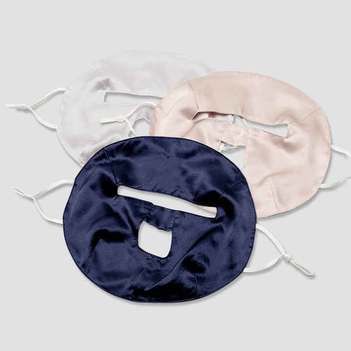 Three Beauty Silk Face Masks by SusanSilk, featuring rectangular openings and made from luxurious silk, are shown in white, pink, and dark blue colors, positioned overlapping each other on a plain background.