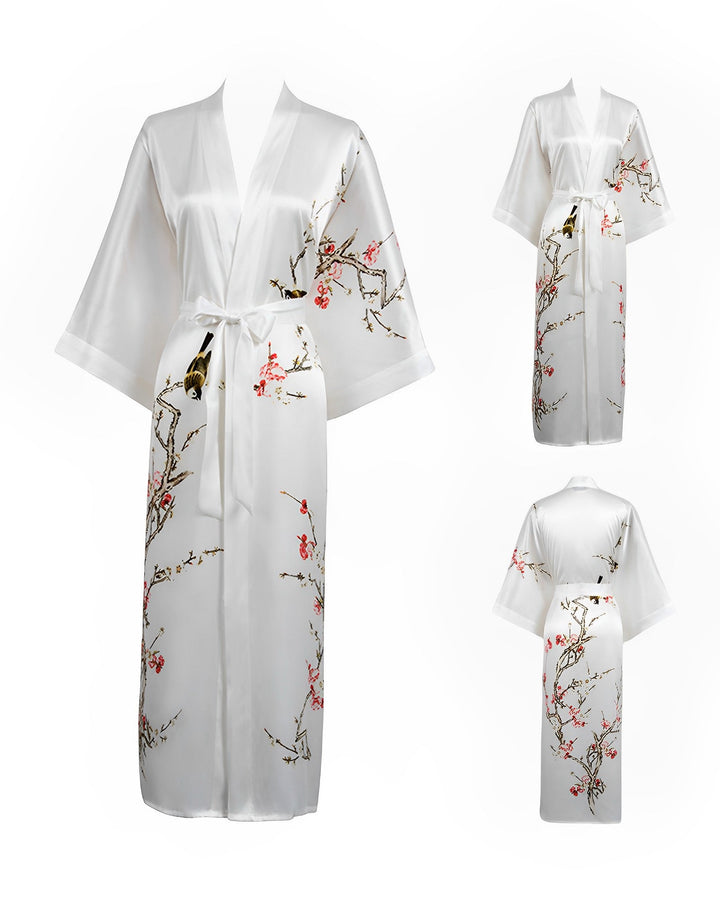 Introducing the Plum Blossom Long Silk Kimono by SusanSilk: a stunning white robe adorned with intricate floral and bird designs on both the front and back. This elegant kimono features wide sleeves and a belt tie at the waist, beautifully showcased in images displaying both front and back views.
