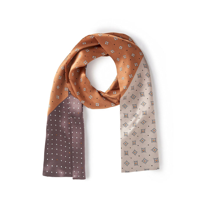 The Tri-Colored Gemstone Narrow Long Silk Scarf by SusanSilk features a luxurious design with a pattern of small squares and dots. This elegant scarf showcases brown, tan, and beige sections adorned with distinct geometric designs.