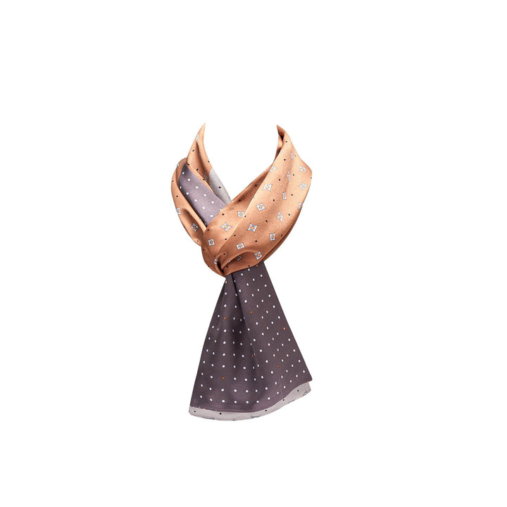 A Tri-Colored Gemstone Narrow Long Silk Scarf from SusanSilk, featuring a dual design: one half in peach with white geometric patterns, and the other in gray with white polka dots. The silk scarf is elegantly draped and knotted in the center.