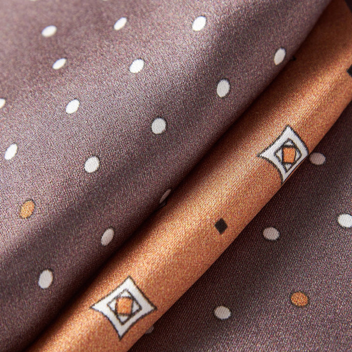Close-up of the Tri-Colored Gemstone Narrow Long Silk Scarf by SusanSilk, featuring folded silk fabric with a maroon background adorned with white polka dots and a brown border showcasing geometric patterns.